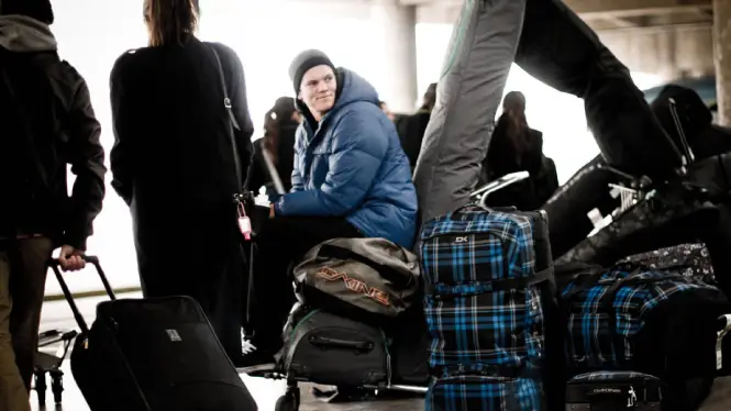 Snowboarder sitting with luggage on his way to do a ski season