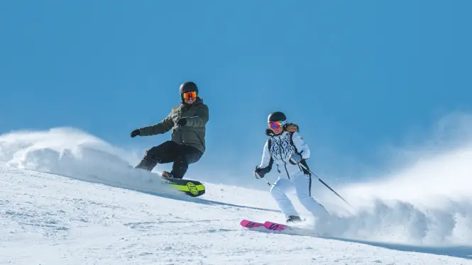 Snowboarder and skier riding in La Plagne
